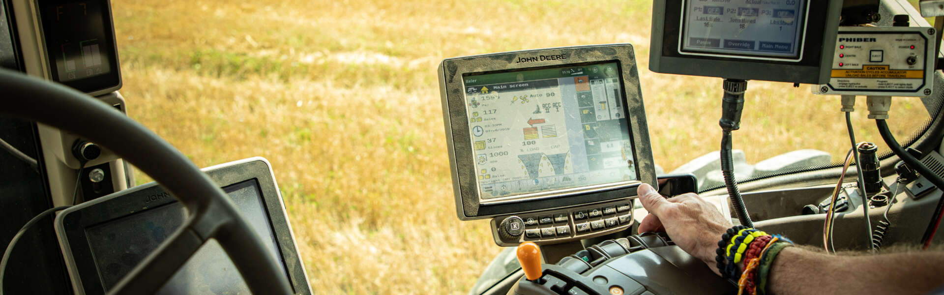 The inside of a tractor as it drives through a yellow field.