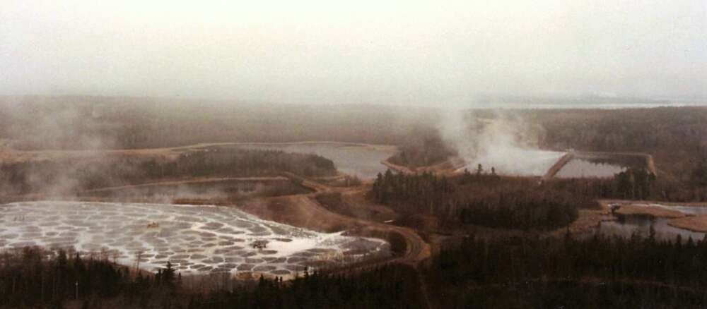 A sepia-toned overhead photo of a pulp mill and reservoirs filled with waste