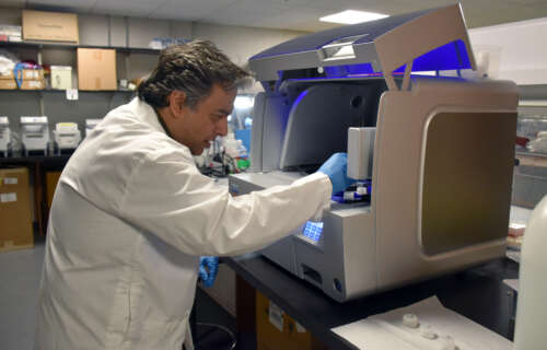 A man in lab boat opens a machine and removes benthos samples