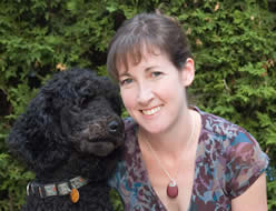 Dr. Shannon Gowland in front of green bushes. On her left is a black dog.