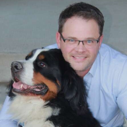 Photo shows Dr. Jason Coe sitting with his dog Harley