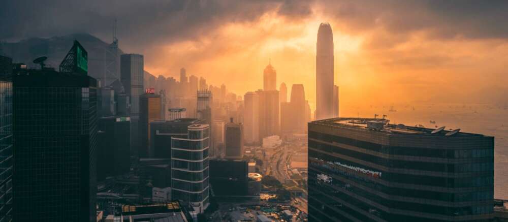 the skyline of Hong Kong with the sun rising through thick clouds