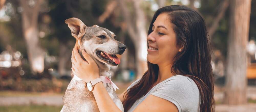 A woman holds their dog in a park