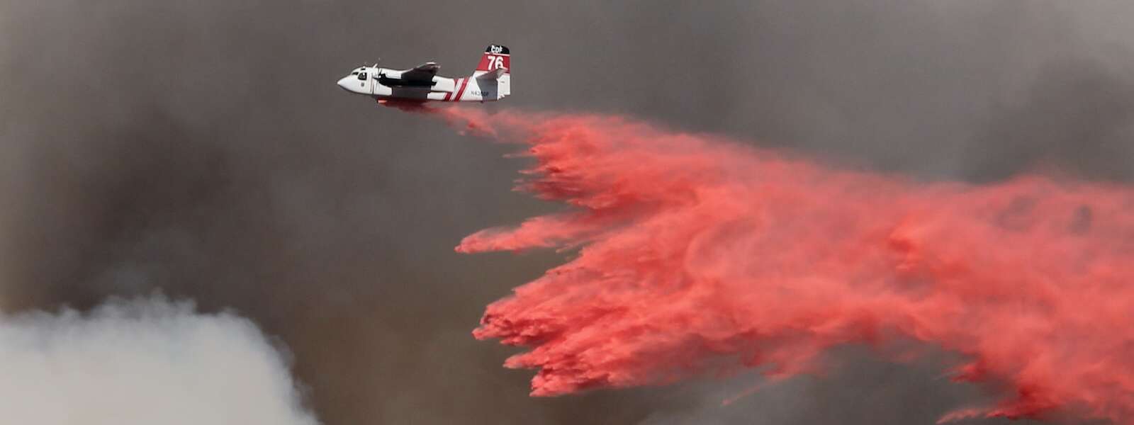 white and red airplane pouring red powder on fire