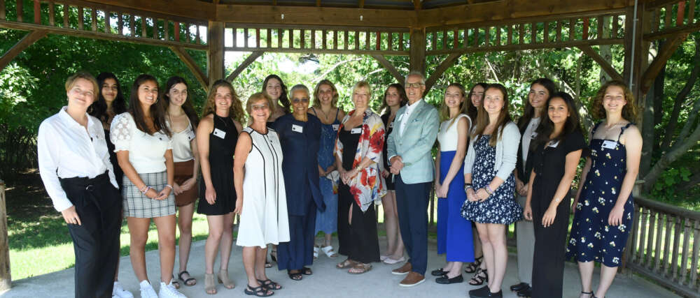 Seventeen people stand in two rows in a gazebo
