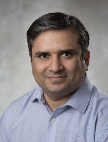 Dr. Khurram Nadeem in light blue collared button-up shirt against light grey background.
