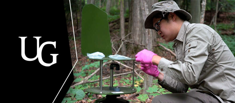 A person crouches in a forest Research technician Chris Ho adjusting a Cyclone air sampler