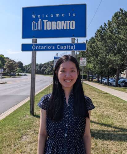 Haohan Zhang stands in front of a 'Welcome to Toronto' sign