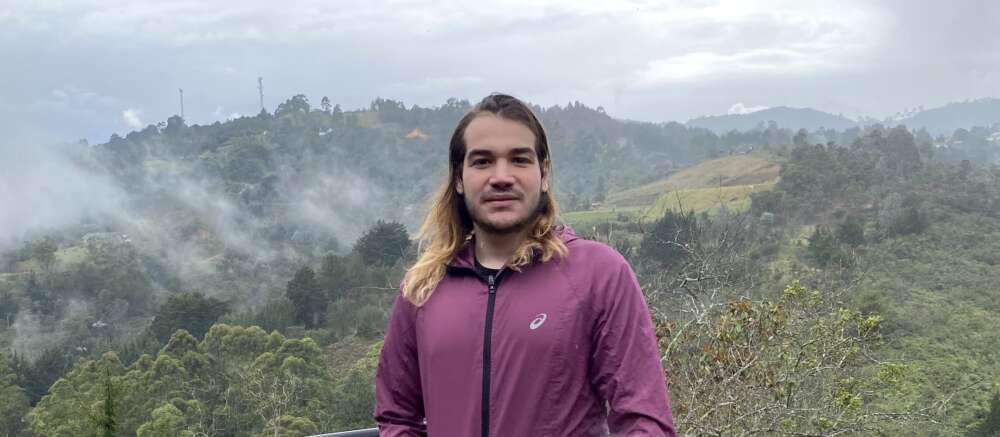 Sebastian Hamid stands ata foggy valley lookout in Colombia