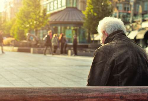man sitting on brown wooden bench