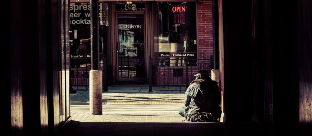 A person sits at the top of a set of stairs in an urban area.