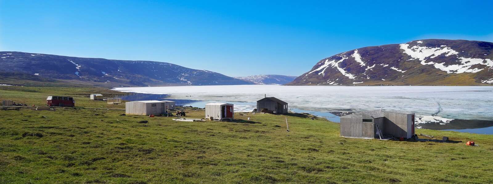 white and brown houses near ice filled water and mountain under blue sky