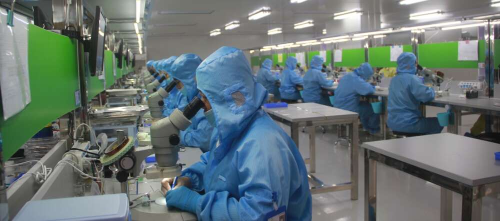 people in blue coveralls and masks work in a factory
