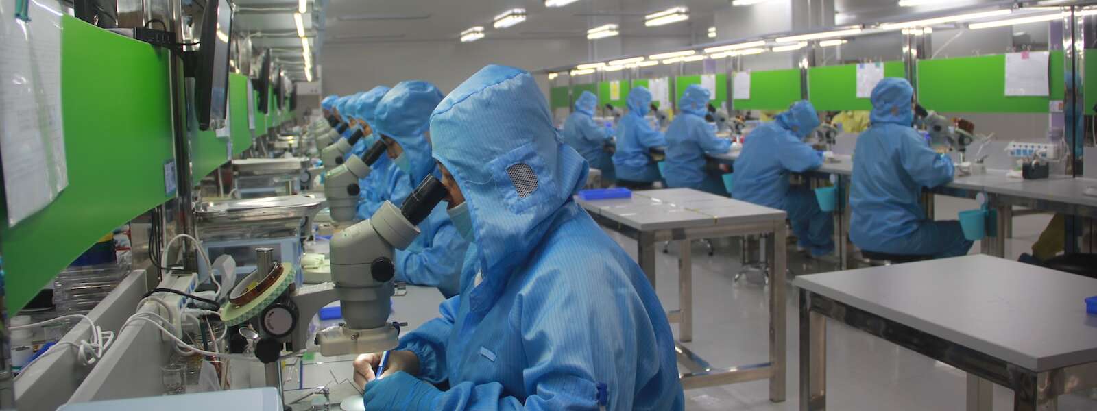 people in blue coveralls and masks work in a factory