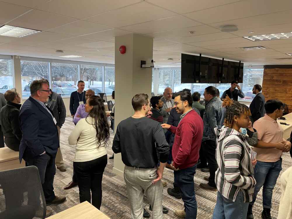 A crowd of attendees mingles in a bright new room in the MCTI Cyber Space