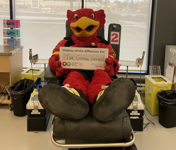 Gryphon mascot in a chair pretending to donate blood