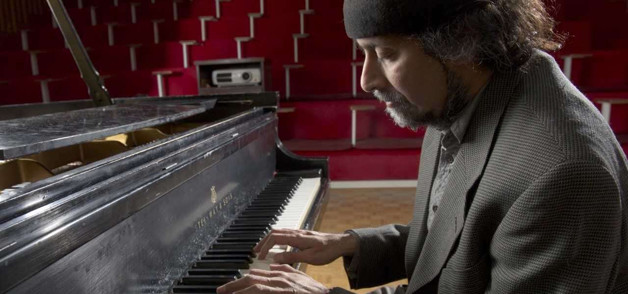 Dr. Ajay Heble plays a grand piano in a theatre
