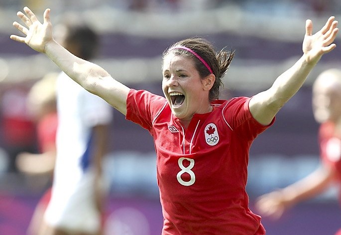 Diana Matheson smiles and holds out her arms in celebration while playing soccer