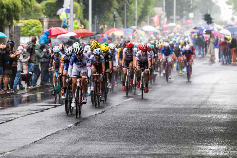 People riding bicycles in a road race during a sun shower