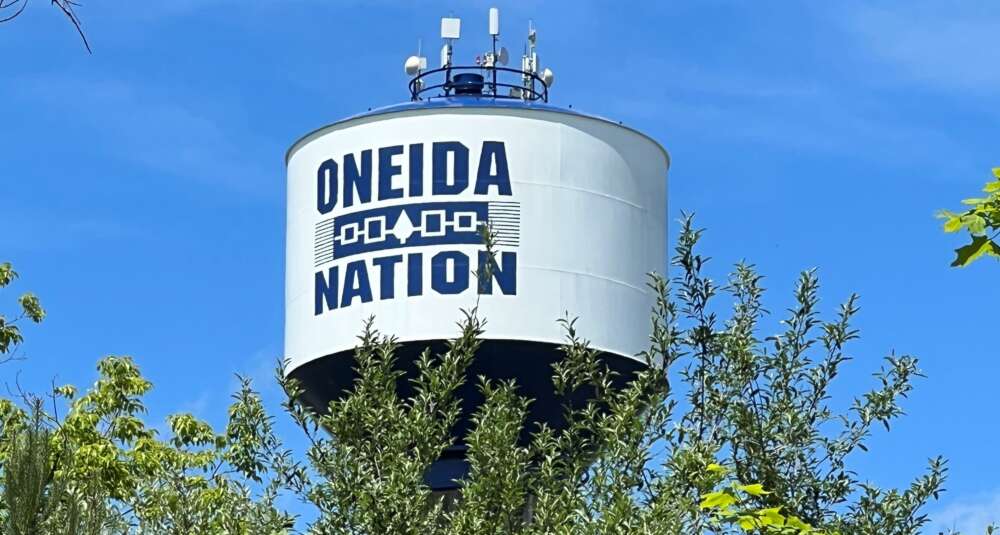 a water tower with the words oneida nation sits above a stand of trees
