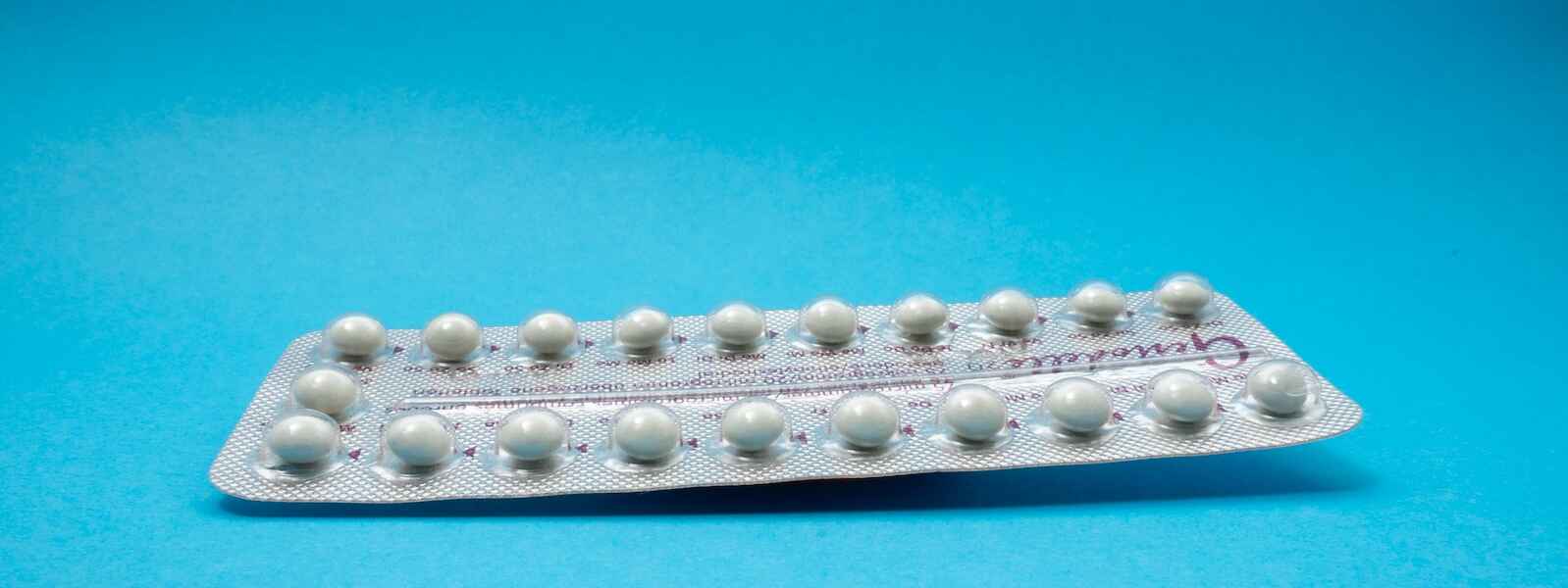 oral contraceptive pill package on a blue backdrop