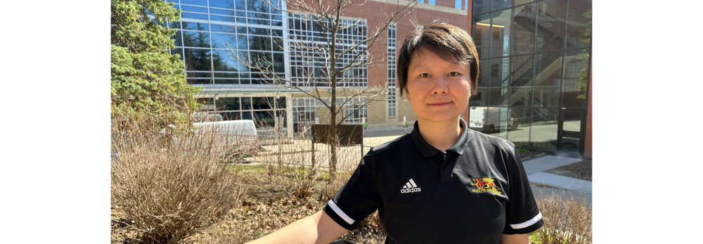 A person stands on stairs on campus with buildings behind