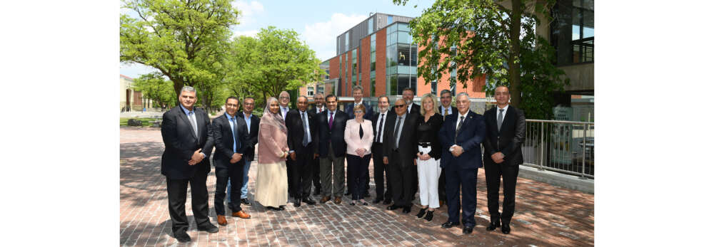 A group of 17 people pose for a photo outside on a sunny day on the University of Guelph campus