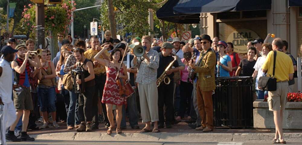A crowd gathers around a jazz band standing on a street corner in Guelph, Ont.
