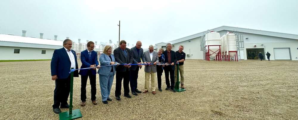 Nine people take part in a ceremonial ribbon cutting in front of the new Ontario Swine Research Centre