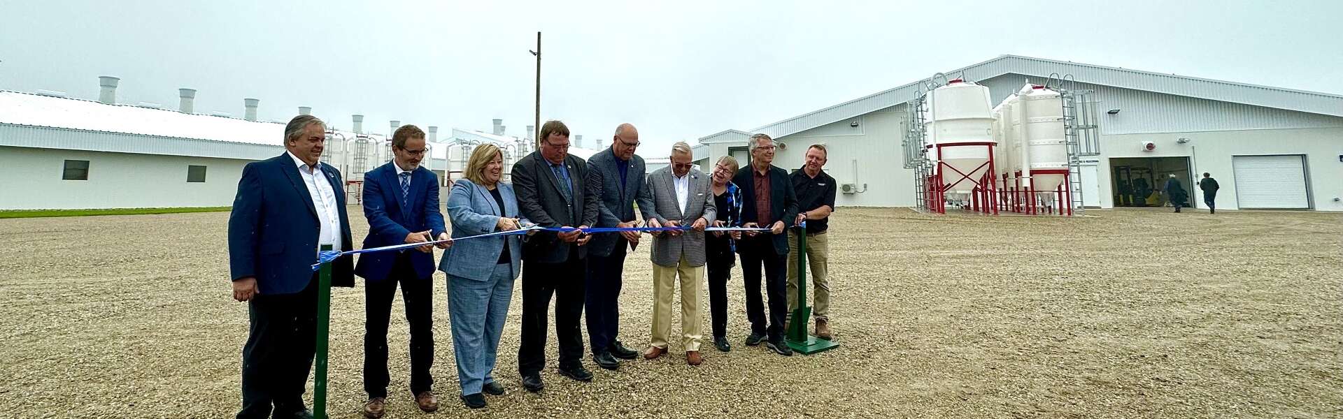 Nine people take part in a ceremonial ribbon cutting in front of the new Ontario Swine Research Centre
