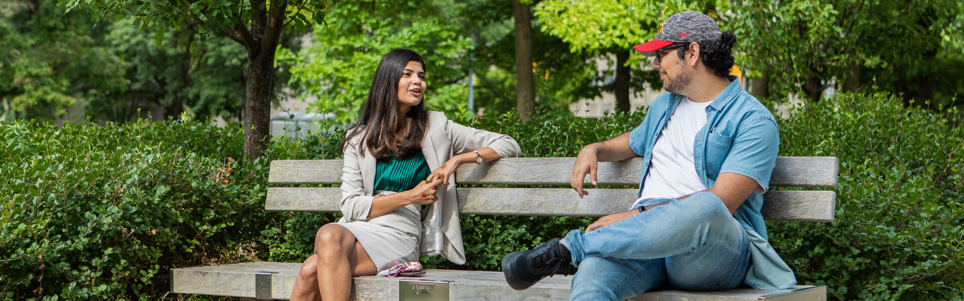 A man and a woman sitting on a park bench, talking.
