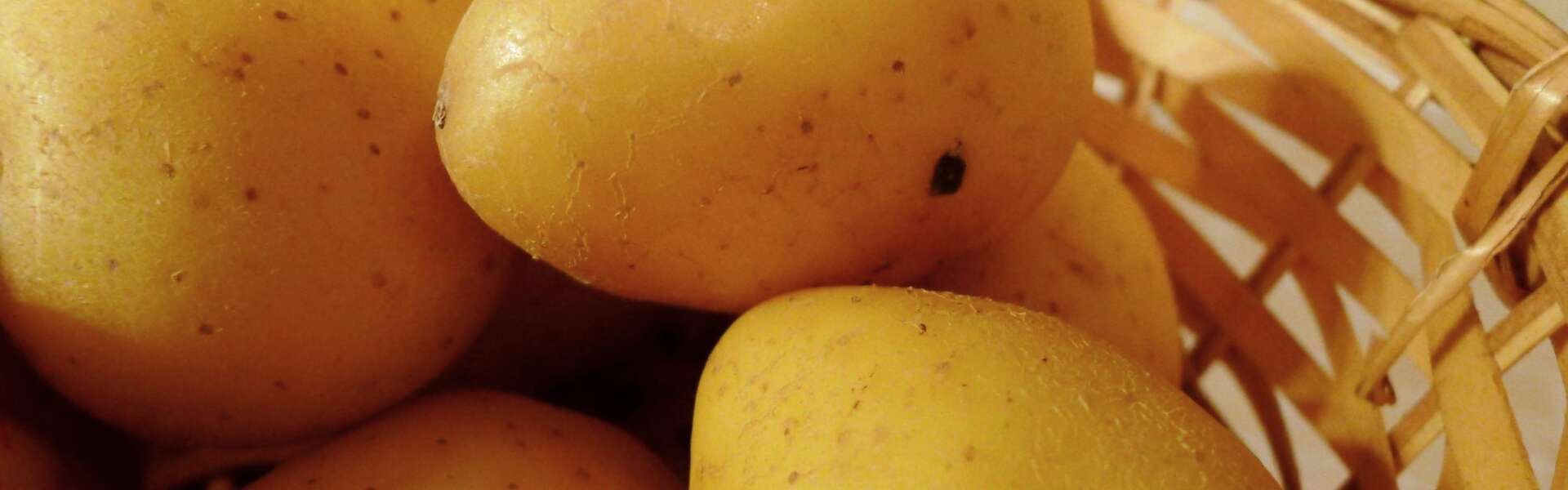 A closeup of a wicker basket full of potatoes