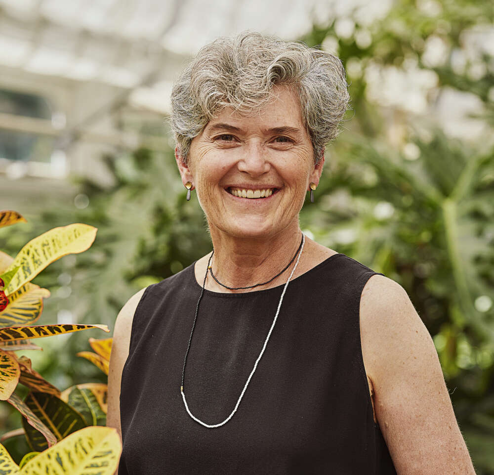 Dr. Beth Parker smiles while standing in a conservatory garden