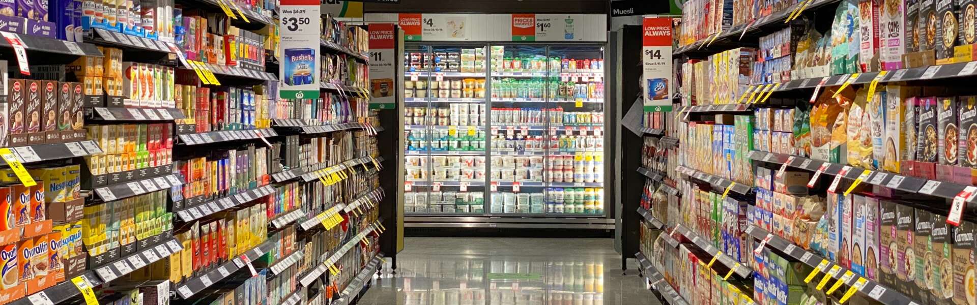 an aisle of a grocery store looking onto the refrigerated section