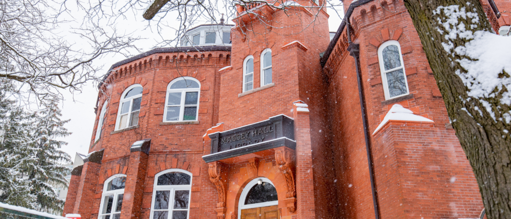The red brick Massey hall on a snowy day.