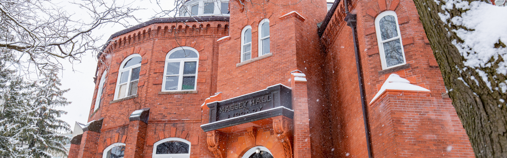 The red brick Massey hall on a snowy day.
