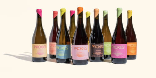 Nine bottles of non-alcoholic wine are placed in staggered rows with labels that depict a rainbow of colours.