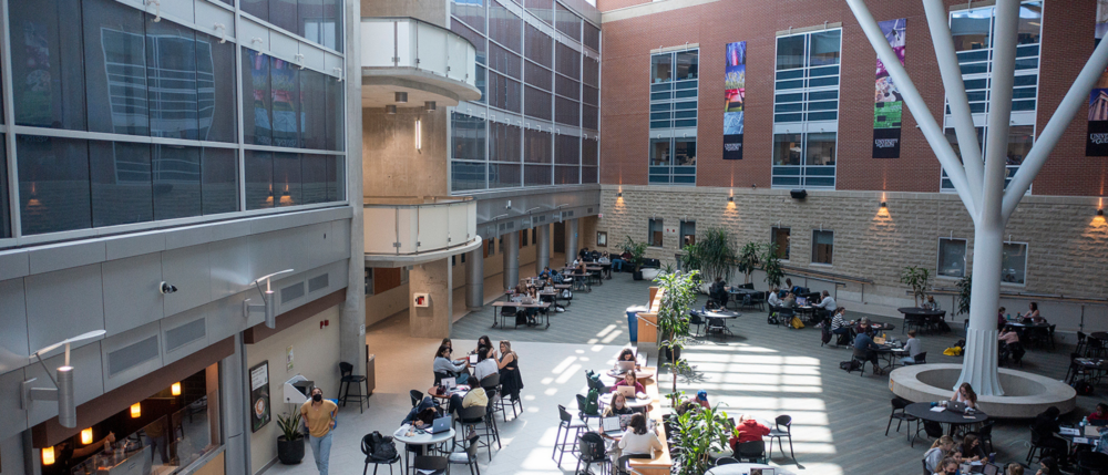 Inside the courtyard of the Summerlee Science Complex as students work at tables.