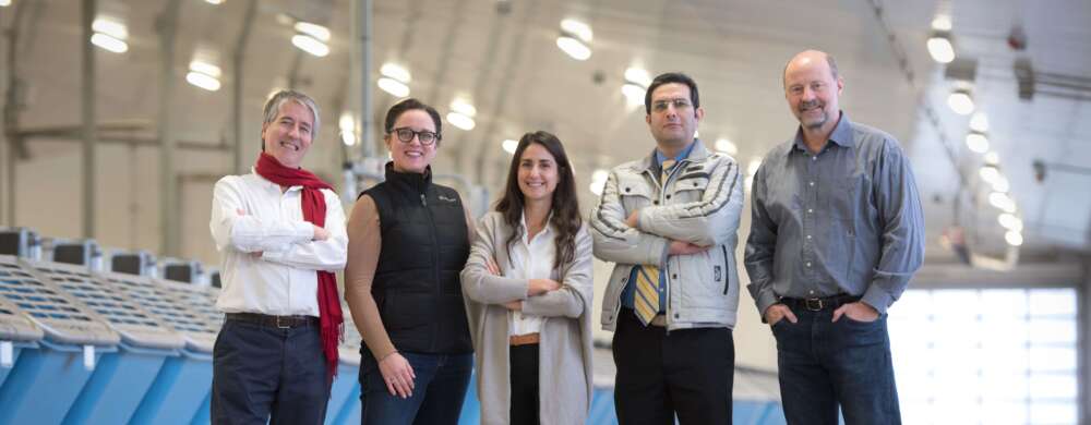 Five people pose for a photo standing in a large dairy barn