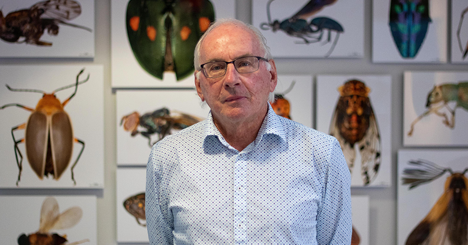 Dr. Paul Hebert poses for a portrait in the atrium of the Centre for Biodiversity Genomics at the University of Guelph with canvas prints of magnified photos of insects hanging on the wall behind him