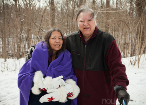 Elders Dan Smoke and Mary Lou Smoke post together in the snowy woods.