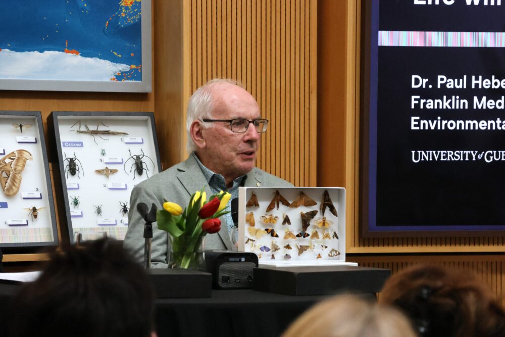 Dr. Paul Hebert shows a box filled with specimens of butterflies and moss to the attendees.