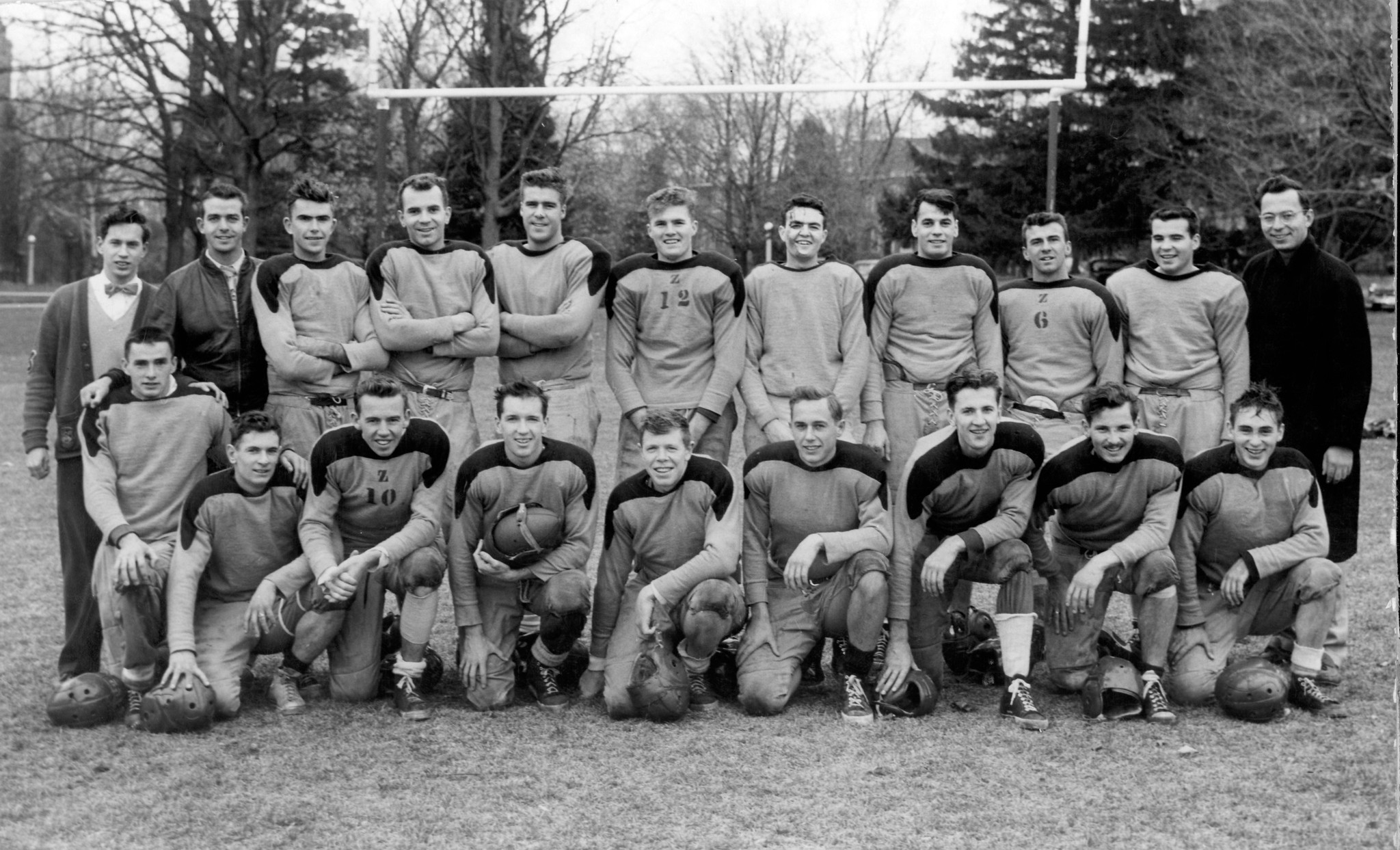 Black and white photo of nearly two dozen members of OAC's 1953 Intramural Football team pose on a field
