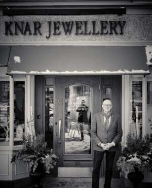 An old black and white photo of a man standing in front of Knar Jewellery.