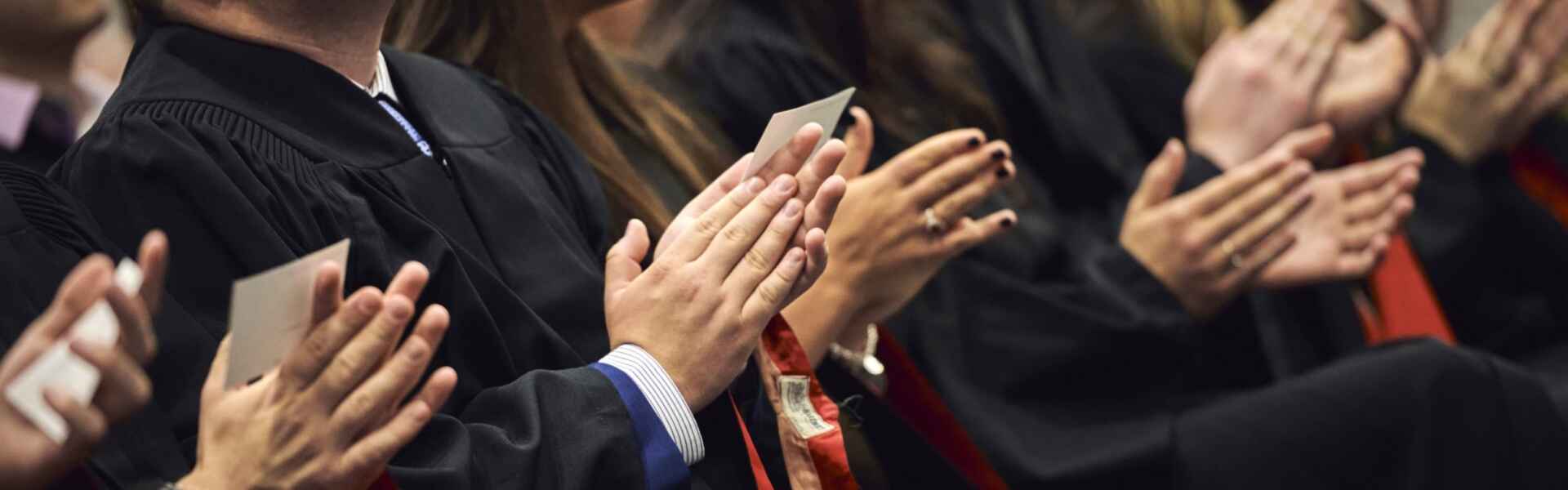 A zoomed-in shot of a row of hands clapping at a convocation ceremony