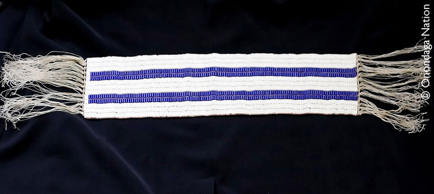 A beaded belt n the belt, two rows of parallel purple lines stretch along a background of white beads.