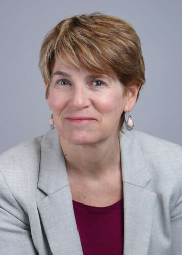 Headshot of Dianne Tyers. She wears a grey blazer and black shirt, has short brown hair and smiles at the camera. 