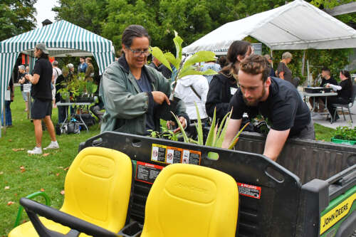 Two people load plants into the back of a 4x4 at the Arboretum expo.