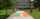 A large pride flag on a sidewalk with McLaughlin Library behind on a sunny day