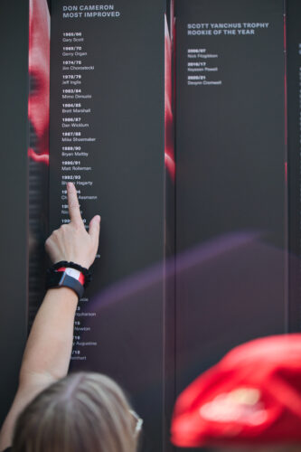 A person points at a name on the Gryphon Football Honour wall.